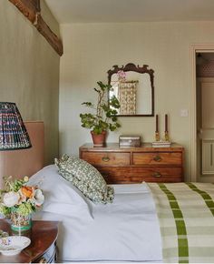 a bedroom with a bed, dresser and mirror on the wall next to each other