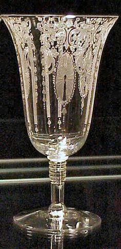 a clear glass vase sitting on top of a black tableclothed surface with an ornate design