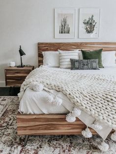 a bed with white blankets and pillows in a room next to two pictures on the wall