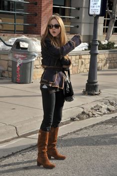 a woman is standing on the street with her hand in her pocket and looking at something