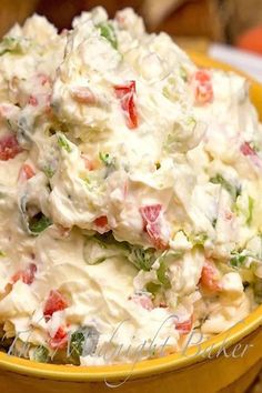 a yellow bowl filled with potato salad on top of a table