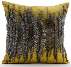 a yellow and black pillow with beads on it