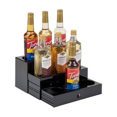 four bottles of liquor are sitting on a black holder that holds six different types of alcohol