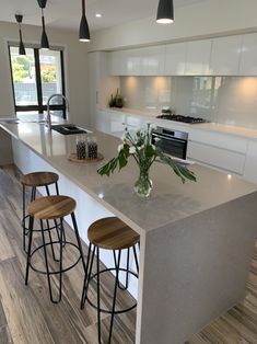 a kitchen island with three stools next to it and a vase on the counter