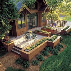 a wooden deck with raised planters on it and an outdoor dining area in the background