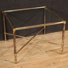 a glass table with gold metal legs on a wooden floor