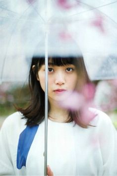 a woman holding an umbrella in front of her face with pink flowers on the outside