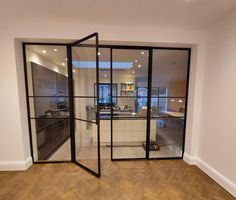 an empty room with glass walls and wood flooring