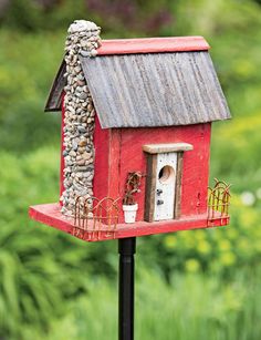 a red bird house on top of a metal pole