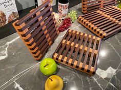 some apples and other fruit sitting on a counter top next to wine bottles, cheese boards, and grapes