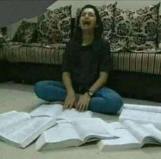 a woman is sitting on the floor with open books in front of her and laughing