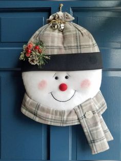 a snowman hat and scarf hanging on a blue door with a plaid scarf around it