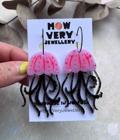 a pair of pink and black octopus earrings on a white card with the words how very jewelry