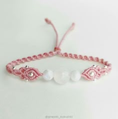 a pink bracelet with white beads and pearls on the end is sitting on a table