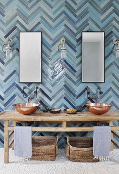 two sinks and mirrors in a bathroom with blue tiles on the wall