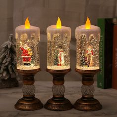 three lit candles sitting on top of a table next to a christmas tree and book