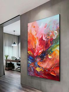 an abstract painting hangs on the wall next to a wooden floor in a living room