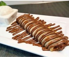 a white plate topped with a sandwich covered in chocolate sauce and drizzled