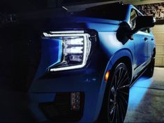 the front end of a blue car parked in a garage with its lights turned on