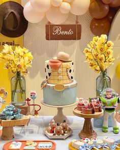 a table topped with lots of cakes and desserts next to balloons in the shape of animals