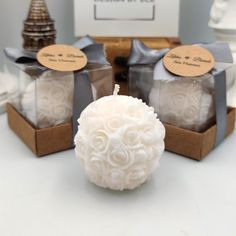 three white candles sitting on top of a table next to some boxes with brown tags