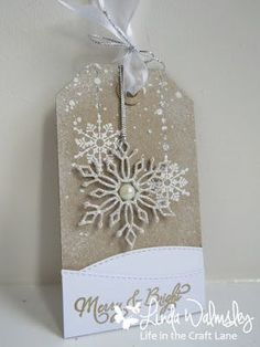 a tag with a snowflake on it hanging from a ribbon attached to a wall