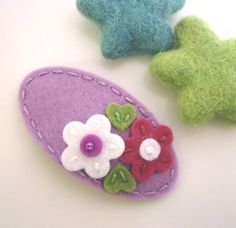 three felt flowers are sitting next to each other on a white surface with green stars