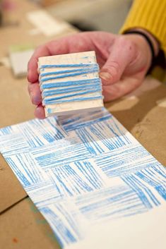 a person is making a piece of paper with blue and white paint on it,