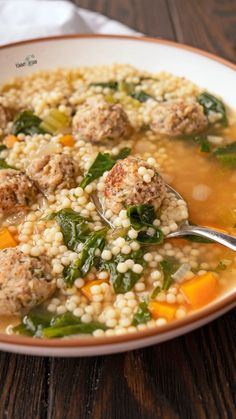 a white bowl filled with soup and meatballs on top of a wooden table next to a napkin