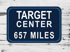 a blue sign that says target center 667 miles on white wooden planks background