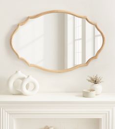 a white mantle with a mirror and vase on top of it next to a fireplace