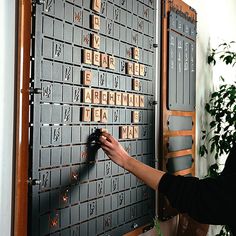 a woman is placing letters on a large metal board with words written on it and holding a small black object in her hand