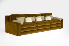 a brown couch with many pillows on it's back and side ends, sitting in front of a white background