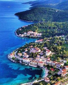 an aerial view of a small village on the shore of a large body of water