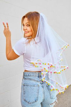 a woman in jeans and a white t - shirt is holding up her peace sign