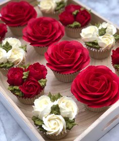 cupcakes decorated with red and white flowers on a tray