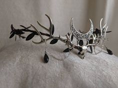 This gorgeous tiara features a haunting, yet beautiful dear skull underneath a filigree crescent moon. Two antlers adorn each side of the dear skull, and delicate chains and crystals fall from the antlers. Leaves surround the flexible branch-like base, and the piece is adjustable with a ribbon in the back. Perfect for cosplay, renaissance fairs, special occasions, or to add a little magic to your everyday! The primary color refers to the leaf and crystal color. Shadow And Bone Halloween Costume, Witchy Wedding Crown, Goth Wedding On A Budget, Moon Based Outfits, Vampire Asethic Outfits, Woodland Goth Aesthetic, Antler Tiara, Dark Faerie Costume, Dark Fantasy Wedding