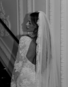 a woman standing in front of a grand piano wearing a wedding dress with veil on her head