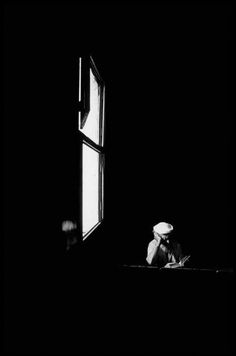 a person sitting at a table in front of a window with an open book on it