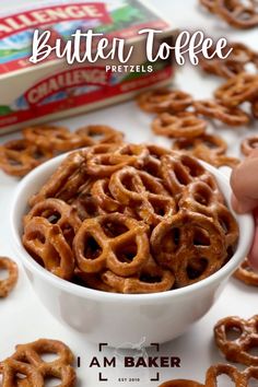 a bowl filled with pretzels sitting on top of a table next to a box of butter