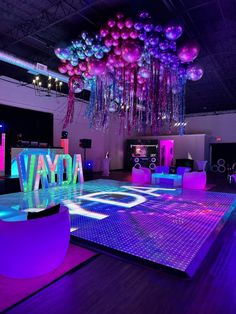 the dance floor is lit up with colorful lights and balloons hanging from it's ceiling