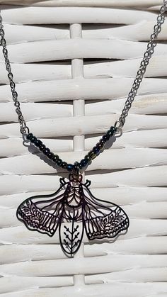 This unique piece features a vibrantly colored, metal moth cutout hanging from a string of multi-colored beads to complement the coloring. The moth is 1 1/4" tall and 1 1/2" wide. These beads attach to a silver chain with lobster clasp that is 18" long. Moth Necklace, The Moth, Handcrafted Ornaments, Christmas Favorites, Be My Valentine, Holiday Collection, Wire Wrapped Jewelry, Resin Art, Earring Necklace