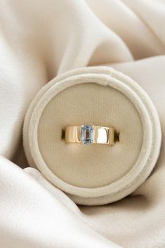 two gold wedding rings sitting on top of a white cloth covered bed sheet, with one ring in the middle