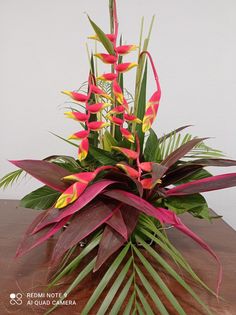 an arrangement of tropical flowers on a wooden table