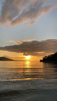 the sun is setting over the ocean with clouds in the sky and water below it