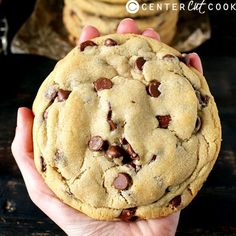 a person holding a chocolate chip cookie in their hand