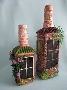 two clay houses made to look like they have windows and plants growing out of them