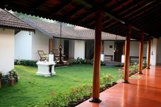 an outside view of a house with grass and flowers in the yard, surrounded by wooden pillars