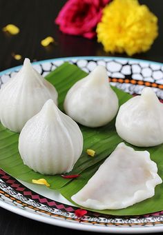 four dumplings on a plate with green leaves and flowers in the backgroud