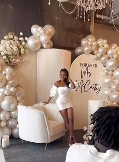 a woman sitting on a chair in front of some balloons and chairs with white flowers